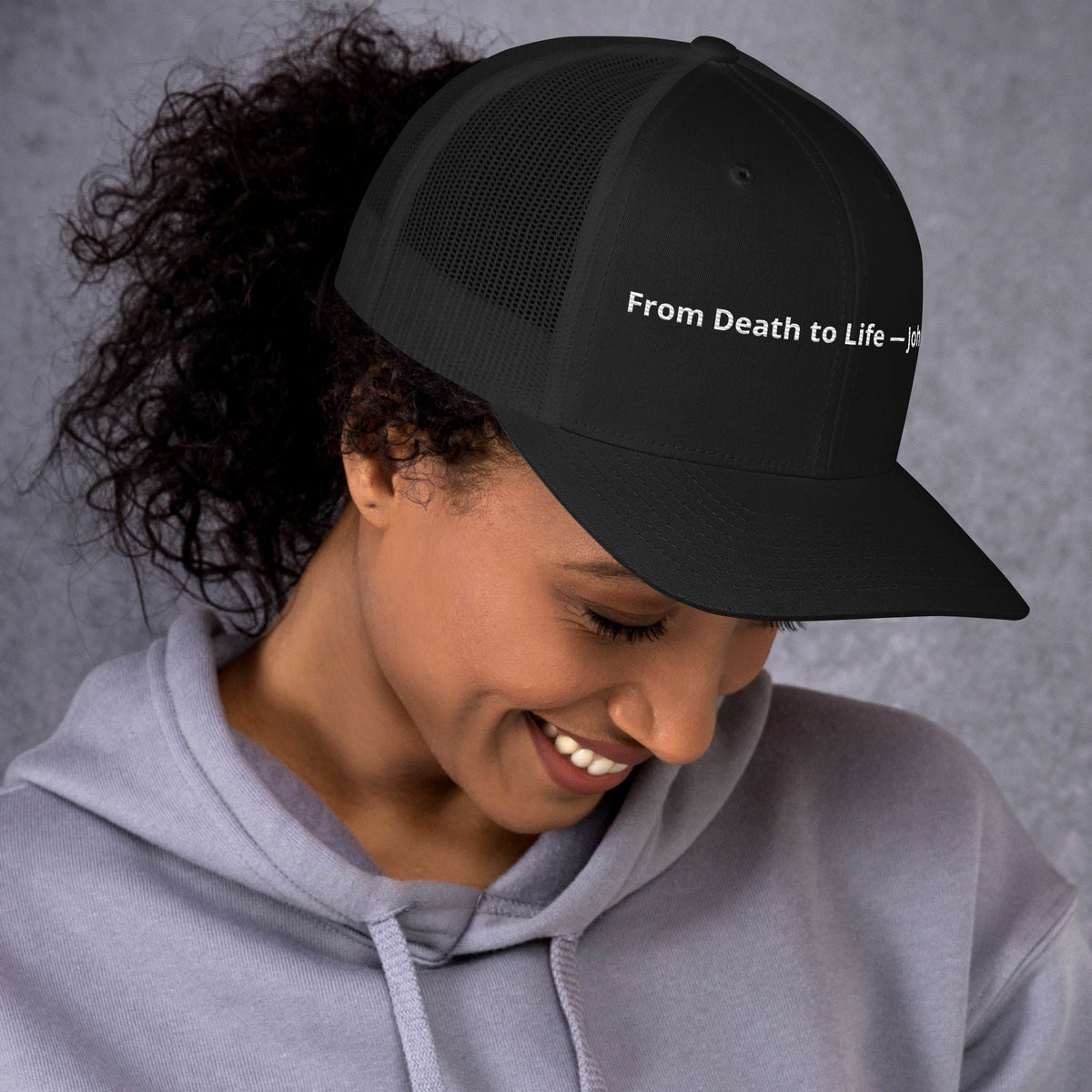 Black retro trucker hat with "From Death to Life" and John 5:24 embroidered text, featuring a curved brim and mesh back.