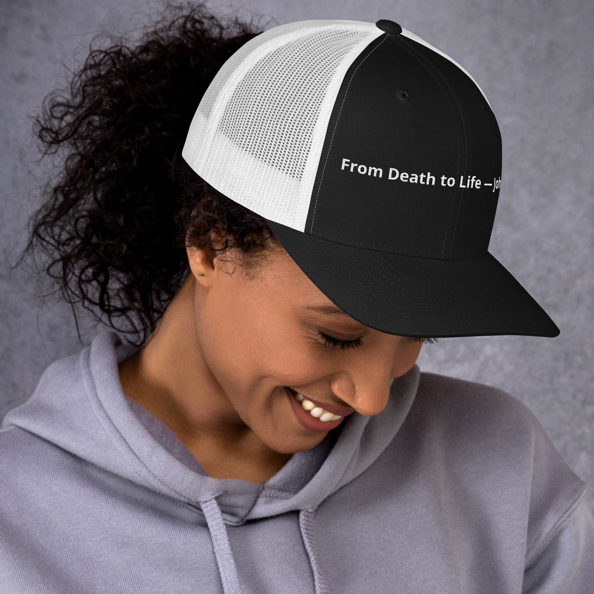 Black and white retro trucker hat featuring From Death to Life John 5:24 scripture design, stylish Christian-themed hat by Tristan's Outlet.